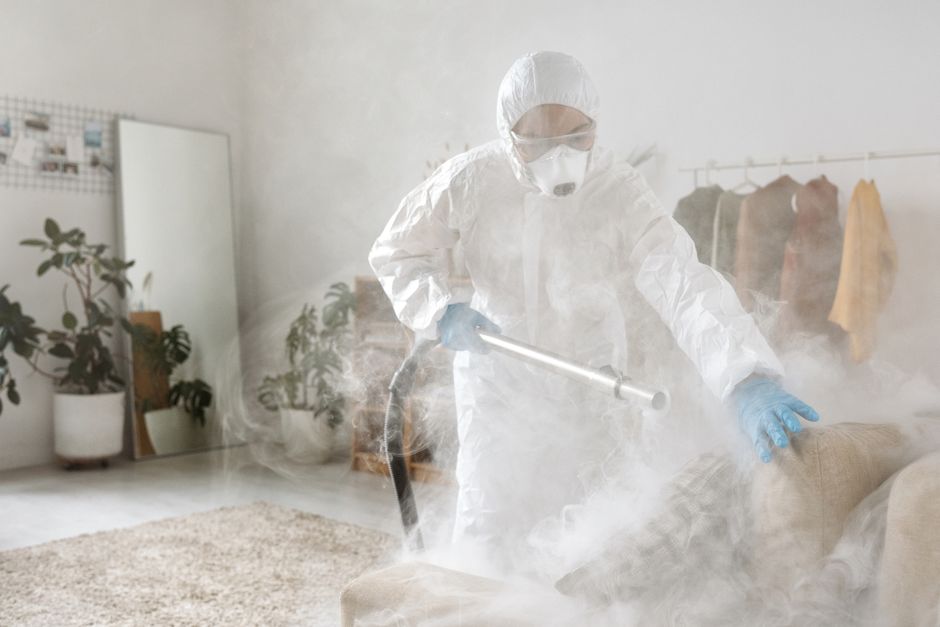 A person in protective suit disinfecting a room to eliminate viruses and bacteria.